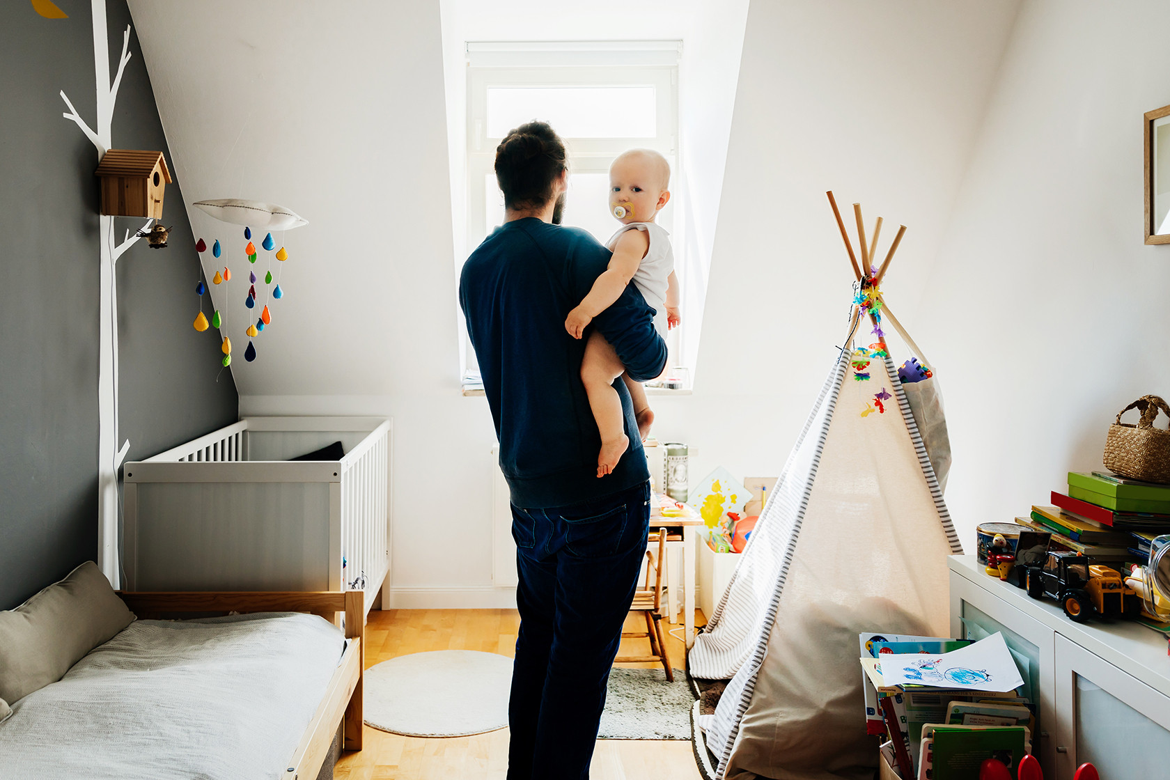 Kleine dakkapel babykamer binnenaanzicht. Vader en baby.